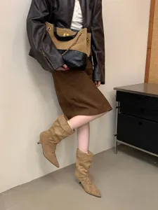 Primer plano de elegantes botas slouchy de punta con tacón fino, presentación de moda en interior.