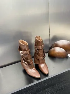 Gros plan de bottines en cuir marron avec plusieurs brides à boucles et rivets.
