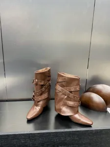 Gros plan de bottes en cuir marron à bout pointu avec multipanières et détails de rivets.
