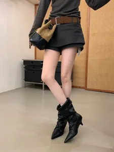 Vista detallada de elegantes botas negras de tacón con punta, calzado de otoño.