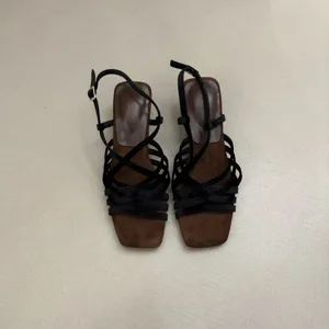 Detail view of women's square toe woven strap high heel sandals, black straps and brown insole.