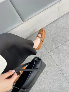 Primo piano dettaglio scarpe basse Mary Jane marroni intrecciate cave traspiranti.