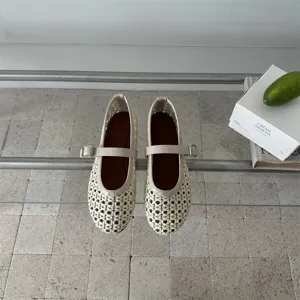Primo piano dettagliato delle scarpe basse Mary Jane intrecciate in bianco crema.