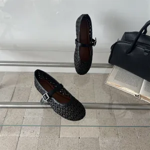 Vista di dettaglio delle scarpe basse Mary Jane nere intrecciate traforate autunnali.