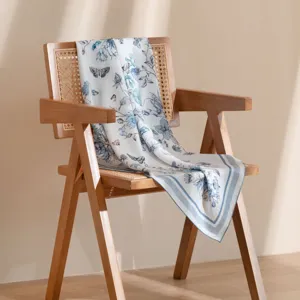 Close-up of mulberry silk square scarf with elegant blue floral and butterfly print details.