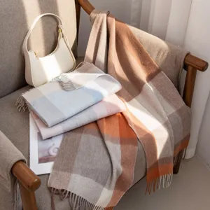 Détail d'écharpe à motif écossais montrant un tissu en laine douce et des franges.