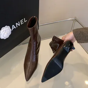 Vista detallada de botas de tacón alto en punta de charol marrón, diseño elegan.