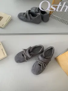 Detailed view of grey suede mary jane casual sneakers with strap and lace design.