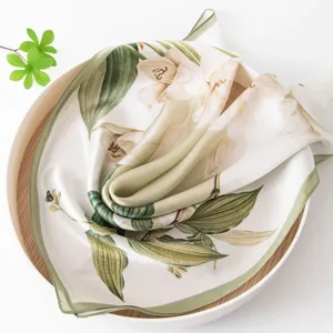 Exquisite silk square scarf with botanical floral print, folded neatly in a decorative tray.
