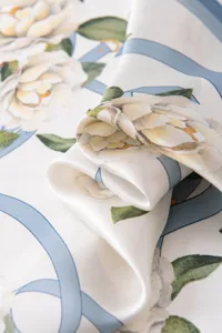 Detailed close-up of mulberry silk square scarf with floral and blue ribbon print texture.