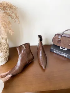 Vue détaillée de bottines marron élégantes à bout pointu posées sur une table en bois.
