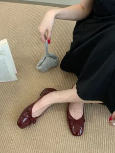 Detailed view of dark red square toe ballet flat shoes with bow, worn in chic scene.