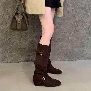 Close-up detail of brown suede slouchy high boots with cross buckle straps, elegant wear.
