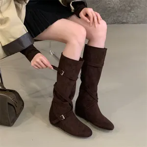 Detailed shot of dark brown suede slouch boots with stylish cross straps and metal buckles.