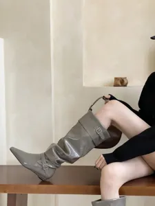 Vista detallada de botas altas de charol para mujer con puntera cuadrada y hebilla.