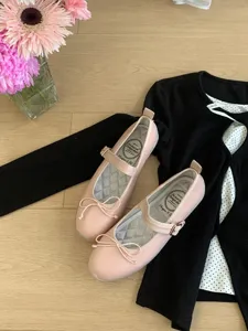 Vue détaillée de chaussures Mary Jane plates roses avec nœud élégant sur sol en bois.