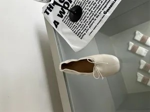 Detail view of stylish beige square toe flat ballet shoes with delicate bow tie for women.