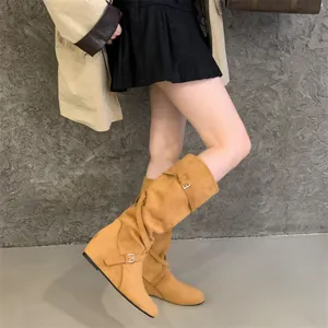 Detailed view of women's suede slouch boots with decorative cross buckle straps and height wedge.