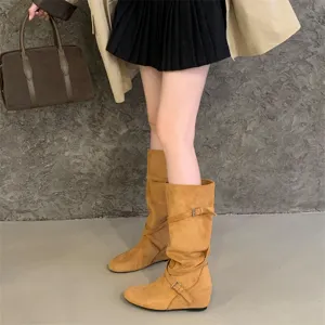 Detailed shot of retro suede slouch boots with cross belt buckles, showing texture and fit.