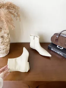 Vue detaillee de bottines ecrues a bout pointu et talons carres bas dans un joli decor.