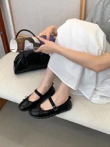 Élégantes chaussures Mary Jane plates et noires avec joli nœud et bride confortable.
