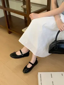 Vue détaillée de chaussures Mary Jane plates noires avec nœud et bride à boucles.