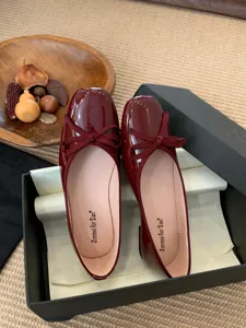 Detail view of burgundy patent leather square toe flat ballet shoes with elegant bow.