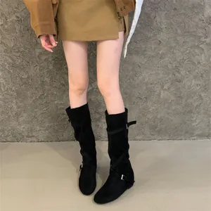 Close up detail of black suede western boots with cross strap buckle design for women.