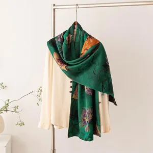 Détail d'écharpe en soie verte, motif floral élégant, texture de tissu luxueuse et drapé.
