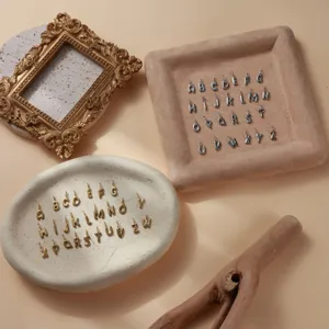 Primo piano di ciondoli con lettere alfabeto 3D in oro e argento, accessori per gioielli.