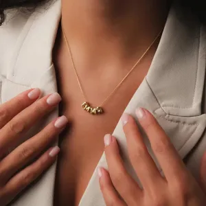 Dettaglio in primo piano di una collana con lettere personalizzate in acciaio inox.