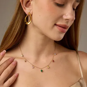 Vergulde organische oorbellen en delicate ketting met kleurrijke steendetails.
