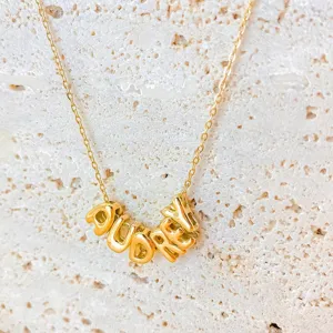 Primo piano di dettaglio della collana con nome a lettere personalizzate in acciaio inox.
