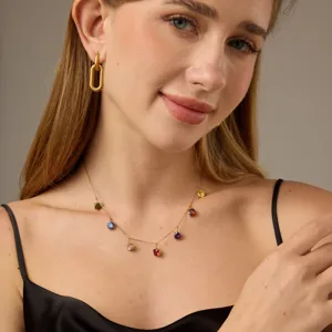 Goudkleurige geometrische oorbellen en kleurrijke stenen ketting closeup detailweergave.