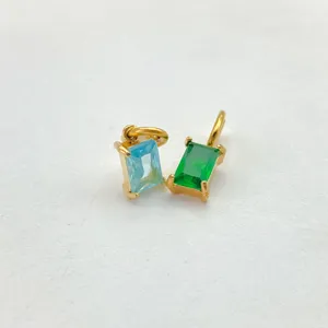 Close up detail of rectangular cubic zirconia gold plated pendant charms in blue and green.