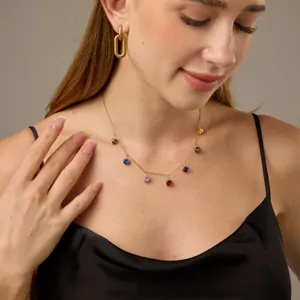 Gedetailleerde opname van een delicate meerkleurige geboortesteenketting gedragen door model.