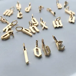 Primo piano dettaglio di charm lettere alfabeto gotico dorati per creazione di gioielli.