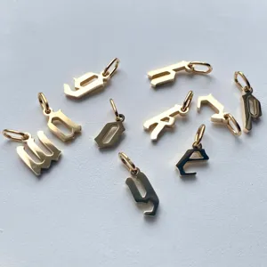 Dettaglio di ciondoli con lettere gotiche dorate, perfetti per collane e bracciali DIY.