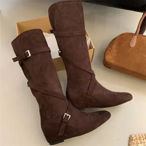 Brown suede knee high boots with buckle strap details and wedge heel closeup view.