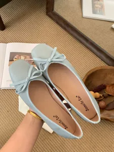 Detail shot of light blue square toe flat ballet shoes with cute bow and soft sole design.