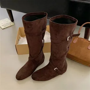 Detailed closeup shot of retro brown suede slouchy high boots with cross buckle straps.