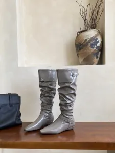 Detalle de botas largas de charol gris, punta cuadrada elegante y tacón plano.