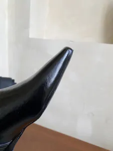 Primer plano detallado de las elegantes botas de mujer de cuero negro con punta cuadrada y acabado.
