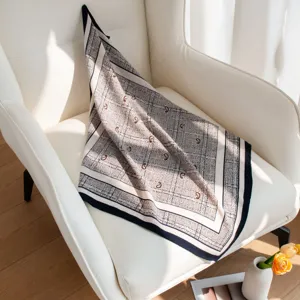 Detailed view of the luxury paisley square scarf draped elegantly on a modern white leather chair.