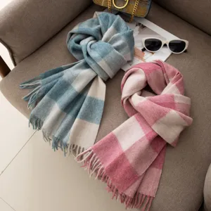 Detail view of stylish autumn winter plaid wool scarf with cute tassels and soft warm fabric.