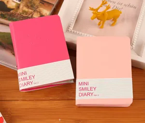 Primer plano de mini cuadernos con cara sonriente en rosa y fucsia con fajas de papel.