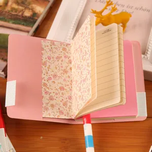 Primer plano detallado del cuaderno portátil rosa con páginas interiores florales y rayas.