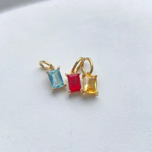 Closeup of geometric square zircon pendants in blue red yellow with gold plated rings DIY.