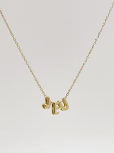 Detailed shot of a stylish gold 3D letter JEU pendant necklace, chic and trendy jewelry.