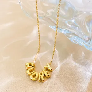 Gold 3D bubble letter pendant necklace, delicate chain, stylish jewelry accessory detail.